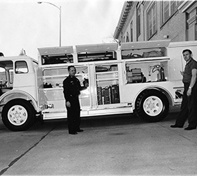 Black and white photo of Greeley firefighters standing with a fire engine