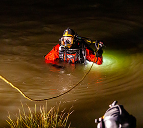 Greeley firefighter in a diving suit in a pond engaged in a water rescue